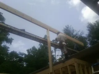 Carpenter setting a ridge beam over a new addition frame — Ice Dam Removal by Roofing Brothers in Runnells