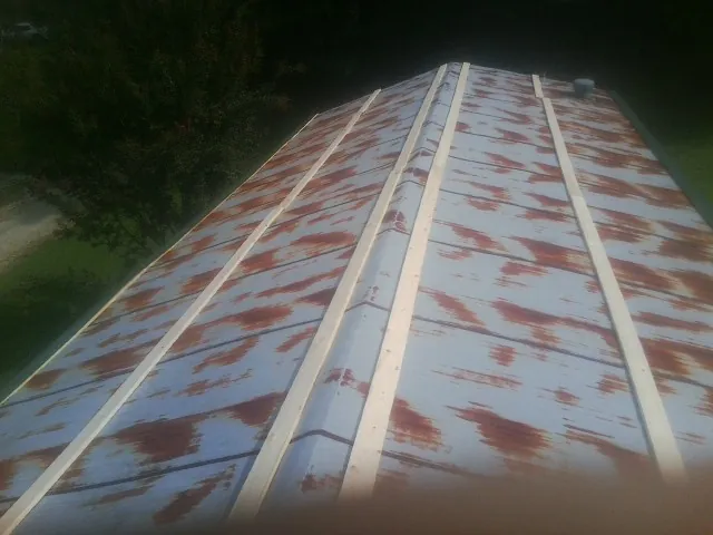 Rusted metal roof panels with new wood purlins before replacement — Storm Damage Roof Repair in Runnells by Roofing Brothers