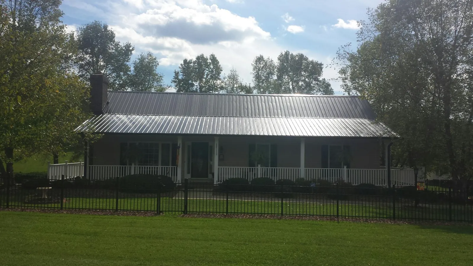 Gray metal roof on a brick ranch with a full width front porch — Gutter Guard Installation work by our crew in Runnells