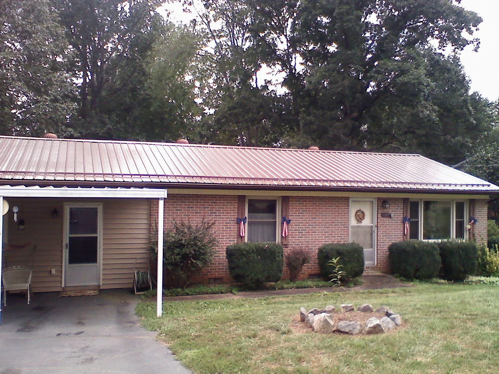 Bronze metal roof and carport on a brick ranch home — Roof Repair work by our crew in Runnells