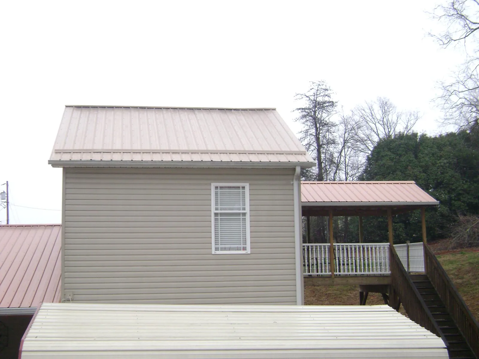 Tan metal roofs on a two story addition and attached porch, from a Roof Replacement job in Runnells